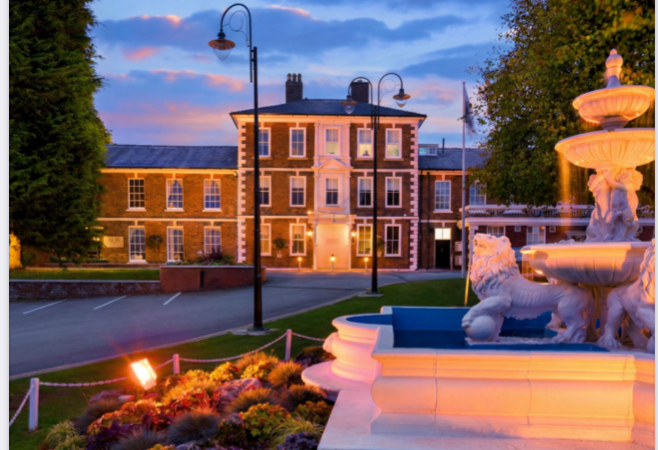 The Grade II listed Georgian façade of the Ramada Park Hall Hotel & Spa at dusk, with its Rococo fountain